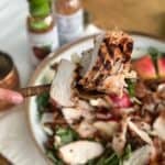 Apple cider marinated chicken sliced on a spoon over salad