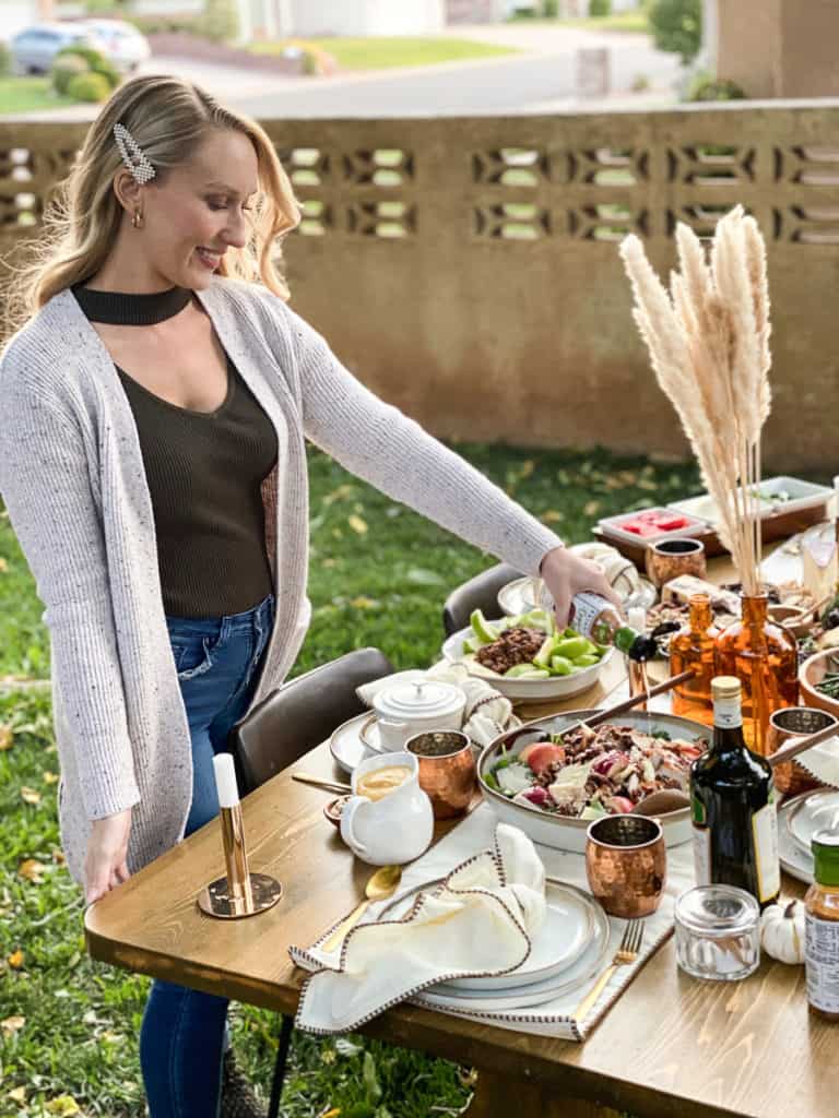 Gal pouring dressing on fall harvest salad