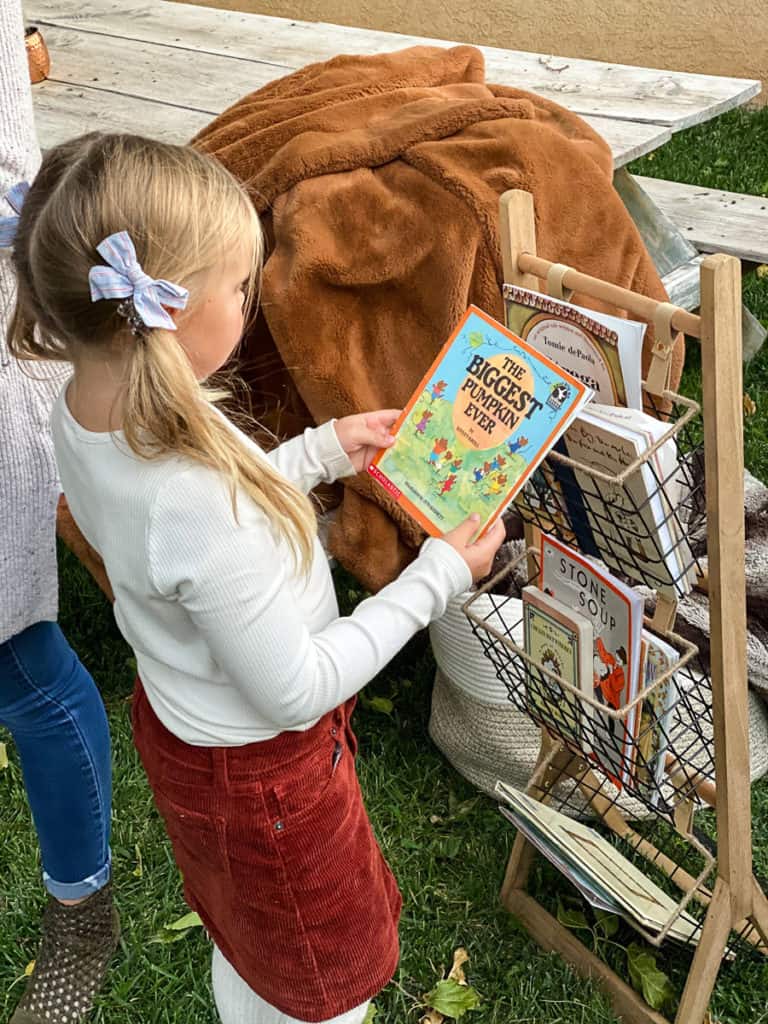 Little girl with pumpkin book outside