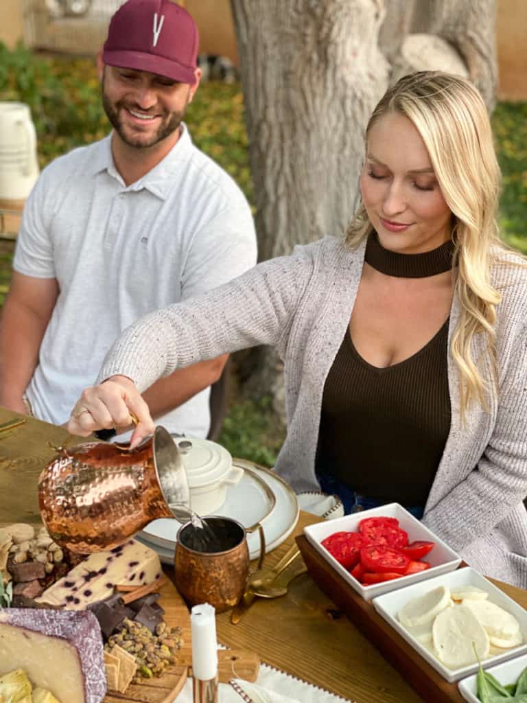 Lady pouring copper pitcher with guy smiling