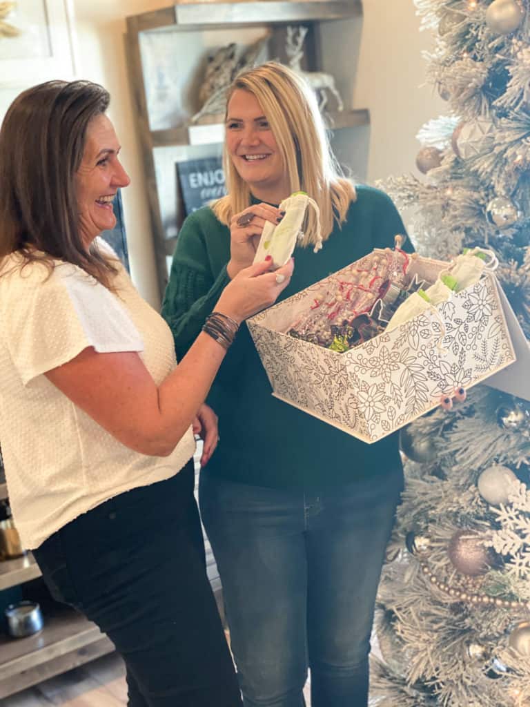 Two women smiling, one gifting the other with a small bag