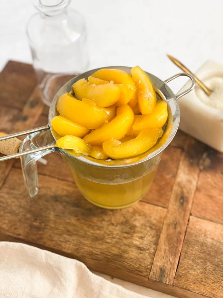 Peach Simple Syrup peaches in a strainer