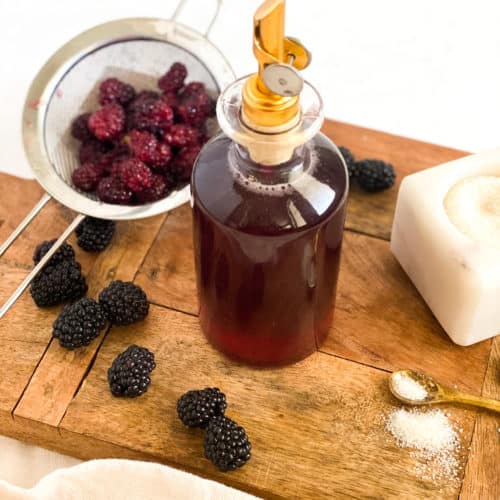 Blackberry Simple Syrup in a glass bottle with berries around