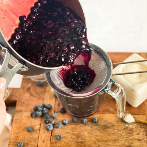 Blueberry Simple Syrup being poured into a strainer