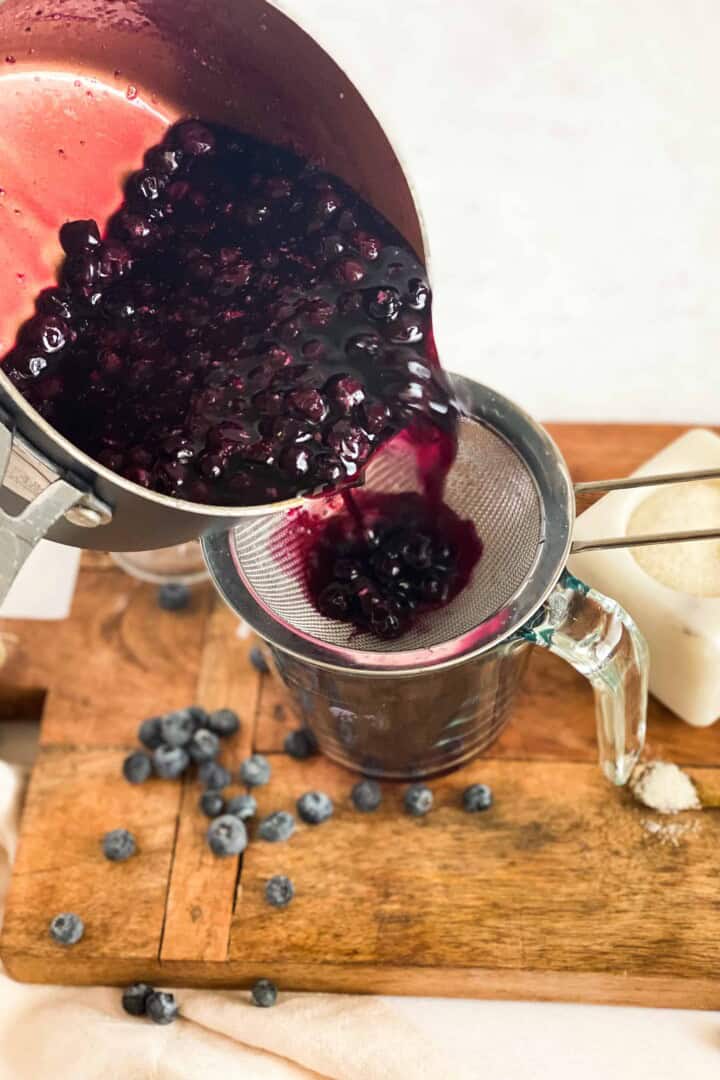 Blueberry Simple Syrup being poured into a strainer