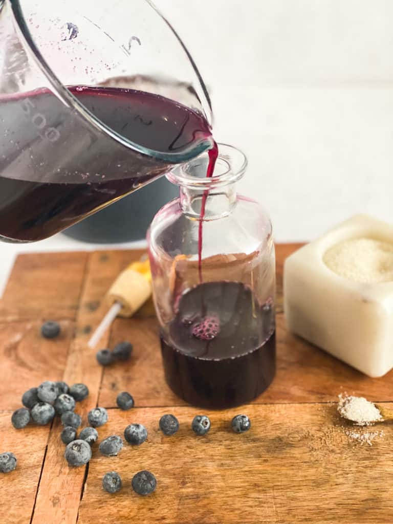 Blueberry Simple Syrup being poured into a glass jar