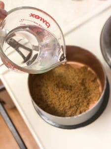 Water being poured into a saucepan with brown sugar