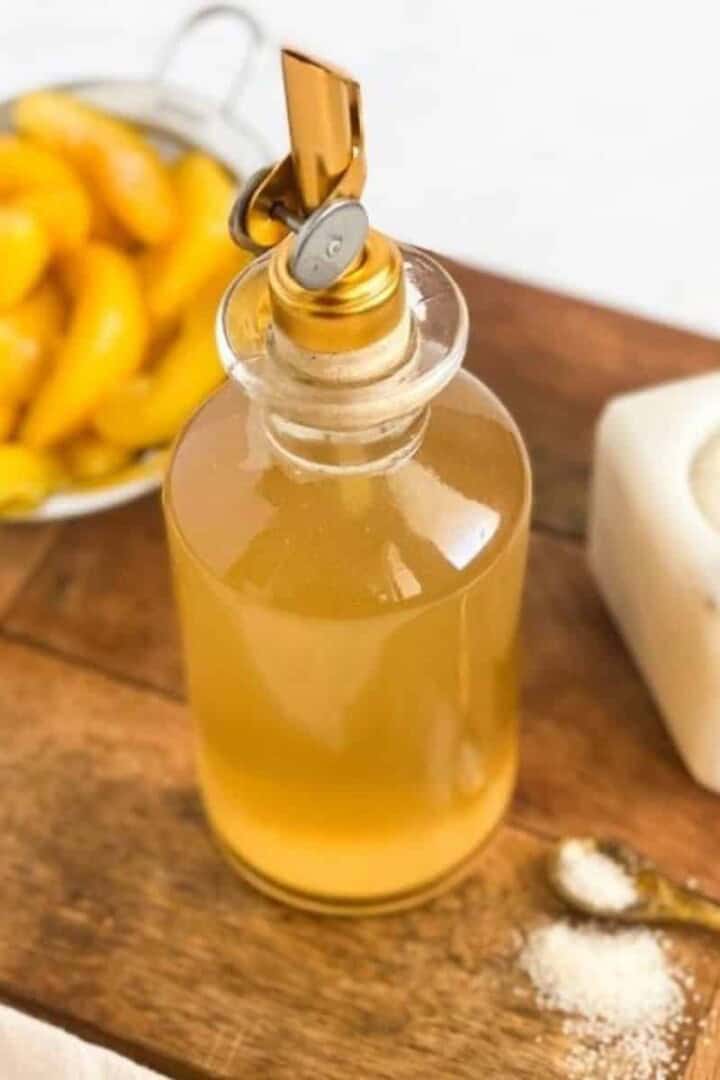 Peach Simple Syrup in a bottle with peaches in a mesh strainer