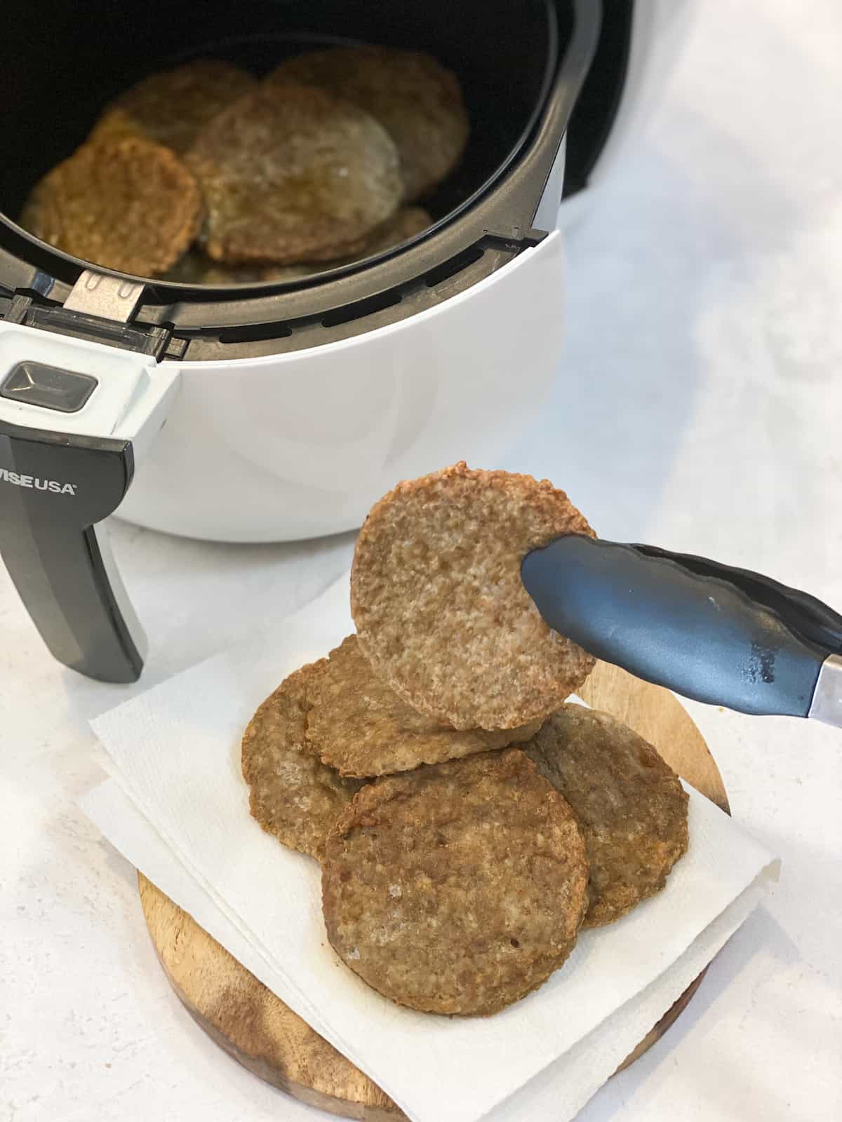 Air Fryer Sausage Patties being picked up with tongs