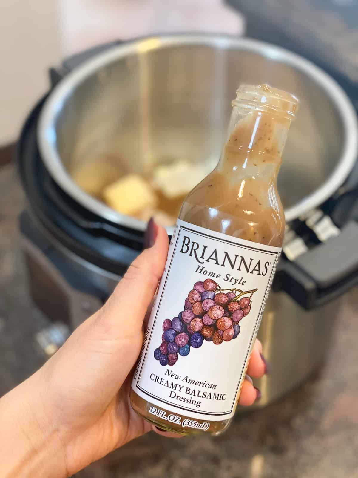 BRIANNAS Creamy Balsamic Dressing in a bottle in a hand