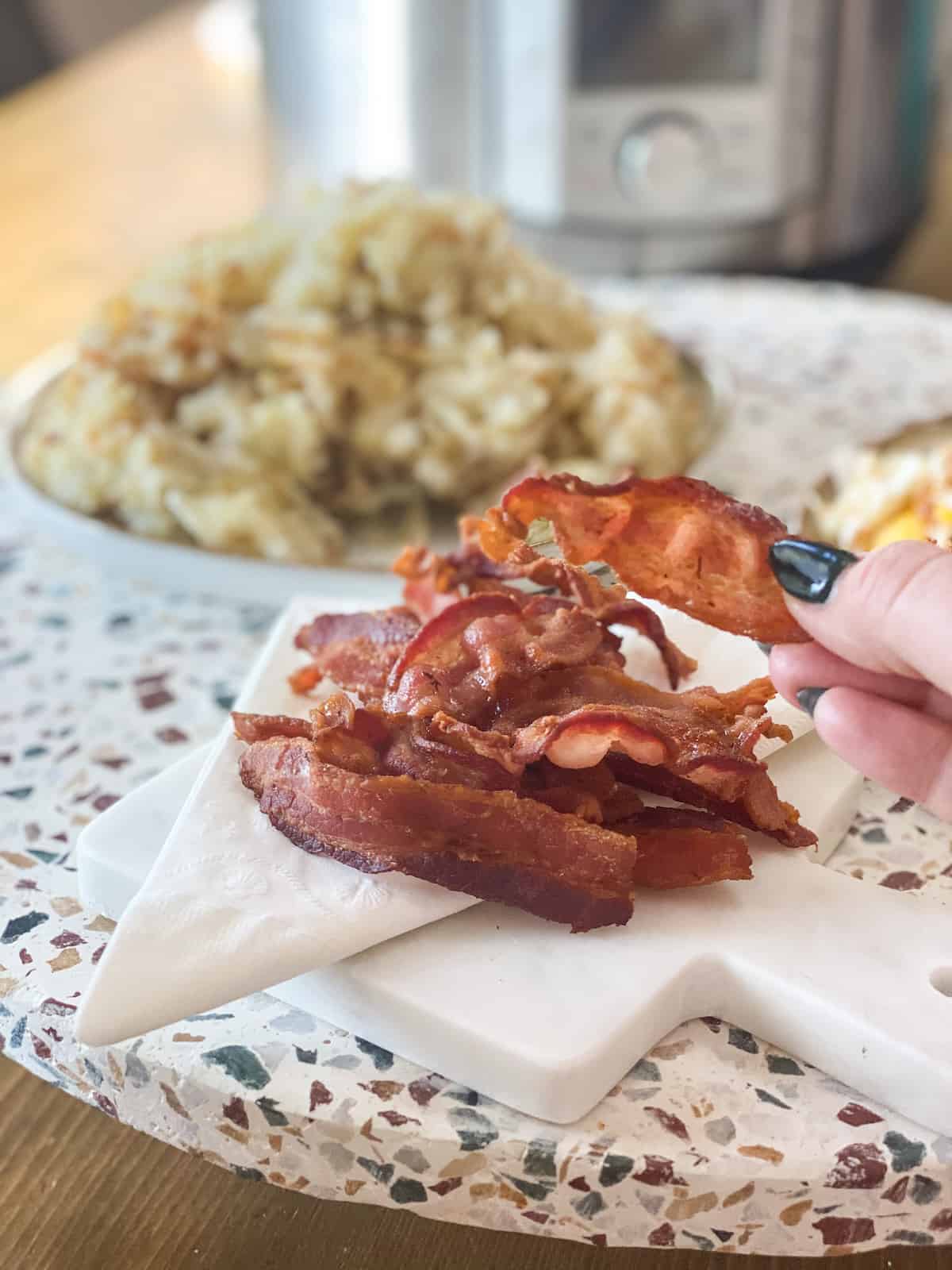 Instant Pot bacon being picked up with a hand