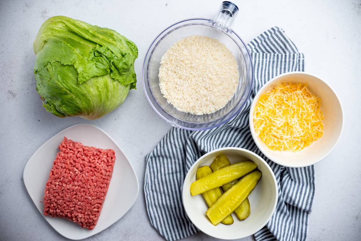 Ground beef, lettuce, rice, cheese and pickles in bowls