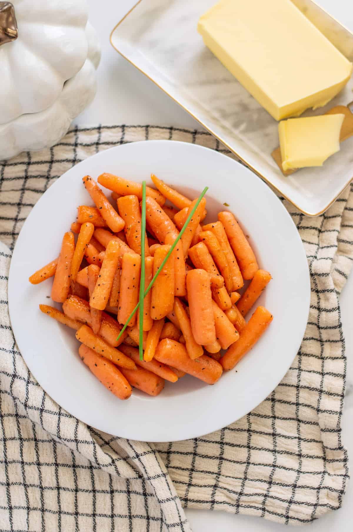 Baby carrots in a white bowl with checkered towel