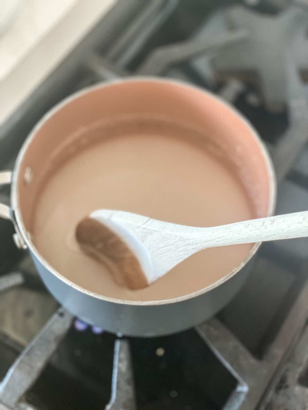 Simple Syrup Recipe being made in a pot with wooden spoon