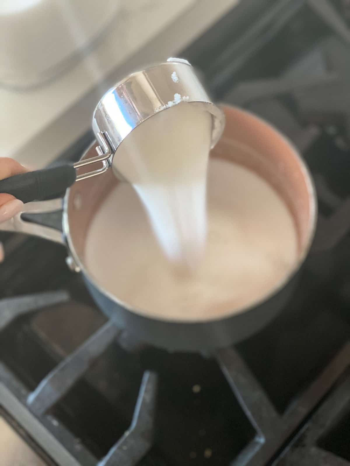 Simple Syrup Recipe being made with sugar being poured into a pot