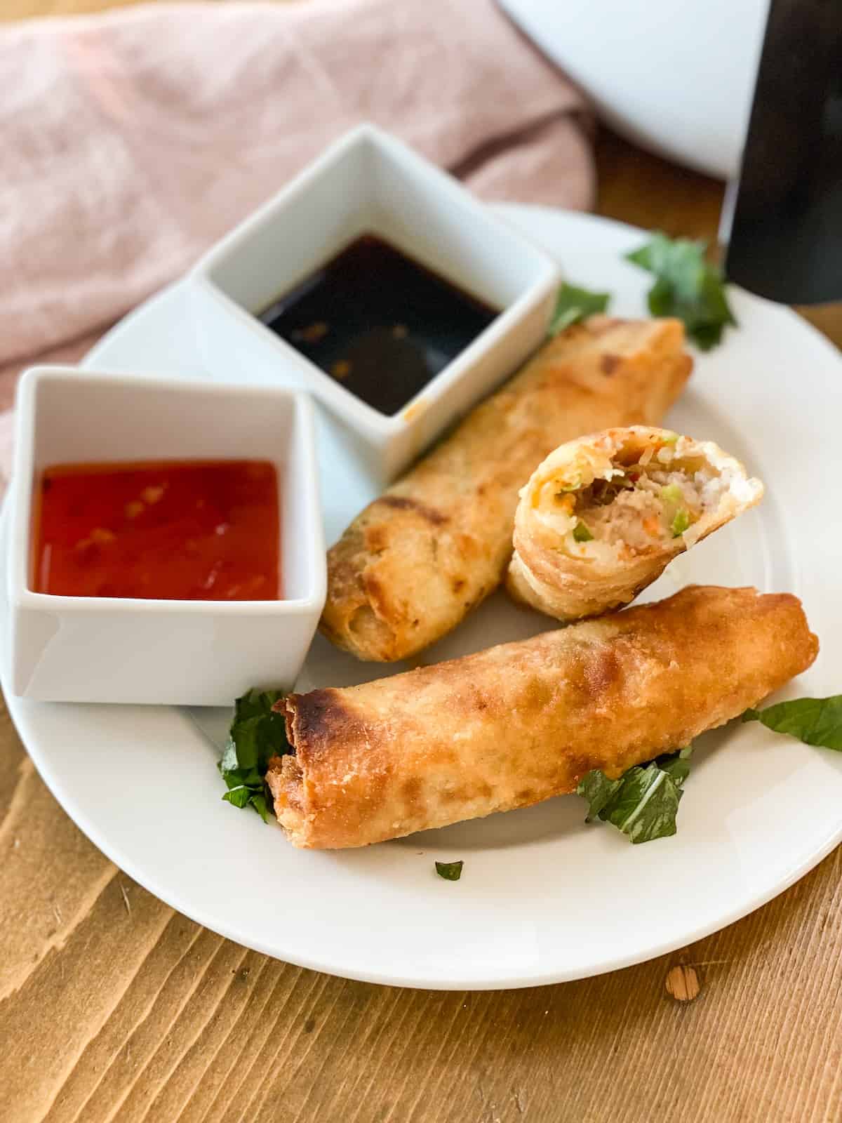 Frozen egg rolls in air fryer cooked then plated on a white plate