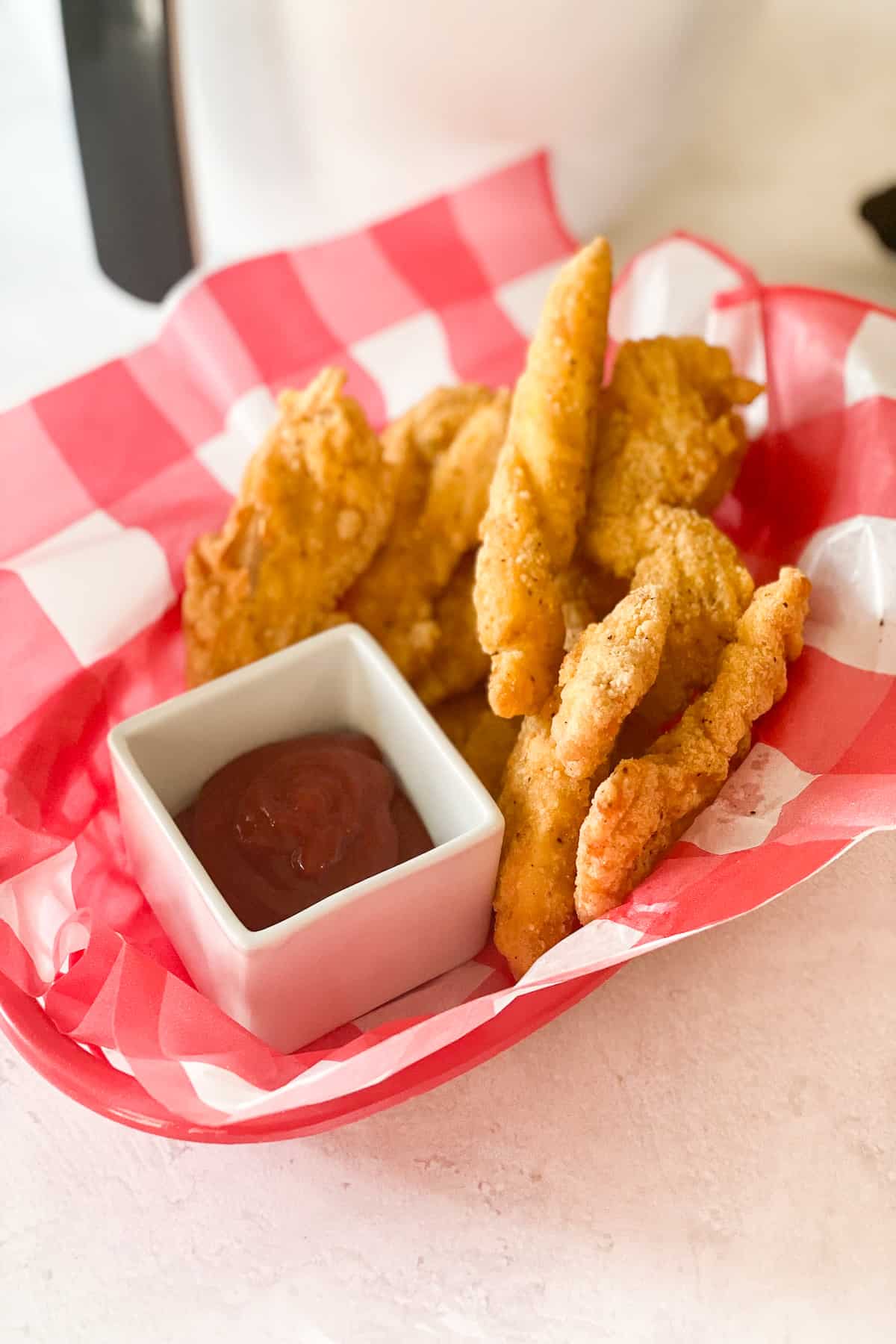 Frozen Chicken Tenders in Air Fryer cooked and in a checkered basket
