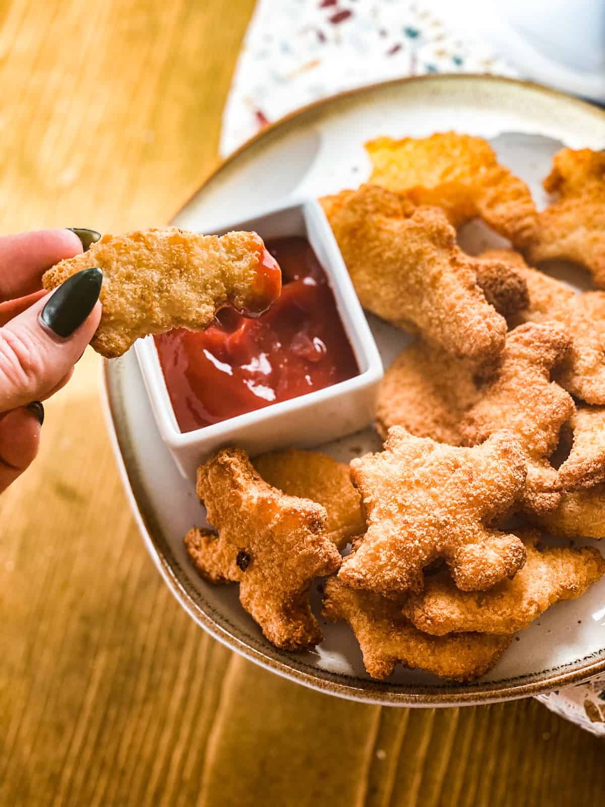 Dino nuggets air fryer style being dipped in ketchup