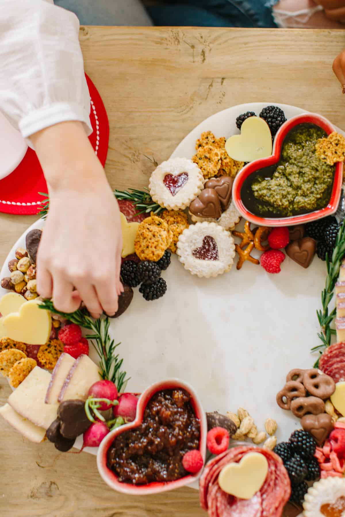 Valentines heart charcuterie board with a hand reaching in for it