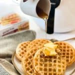 Frozen waffles in air fryer with syrup being poured on them