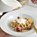 gluten-free rhubarb crisp with cream being poured over it
