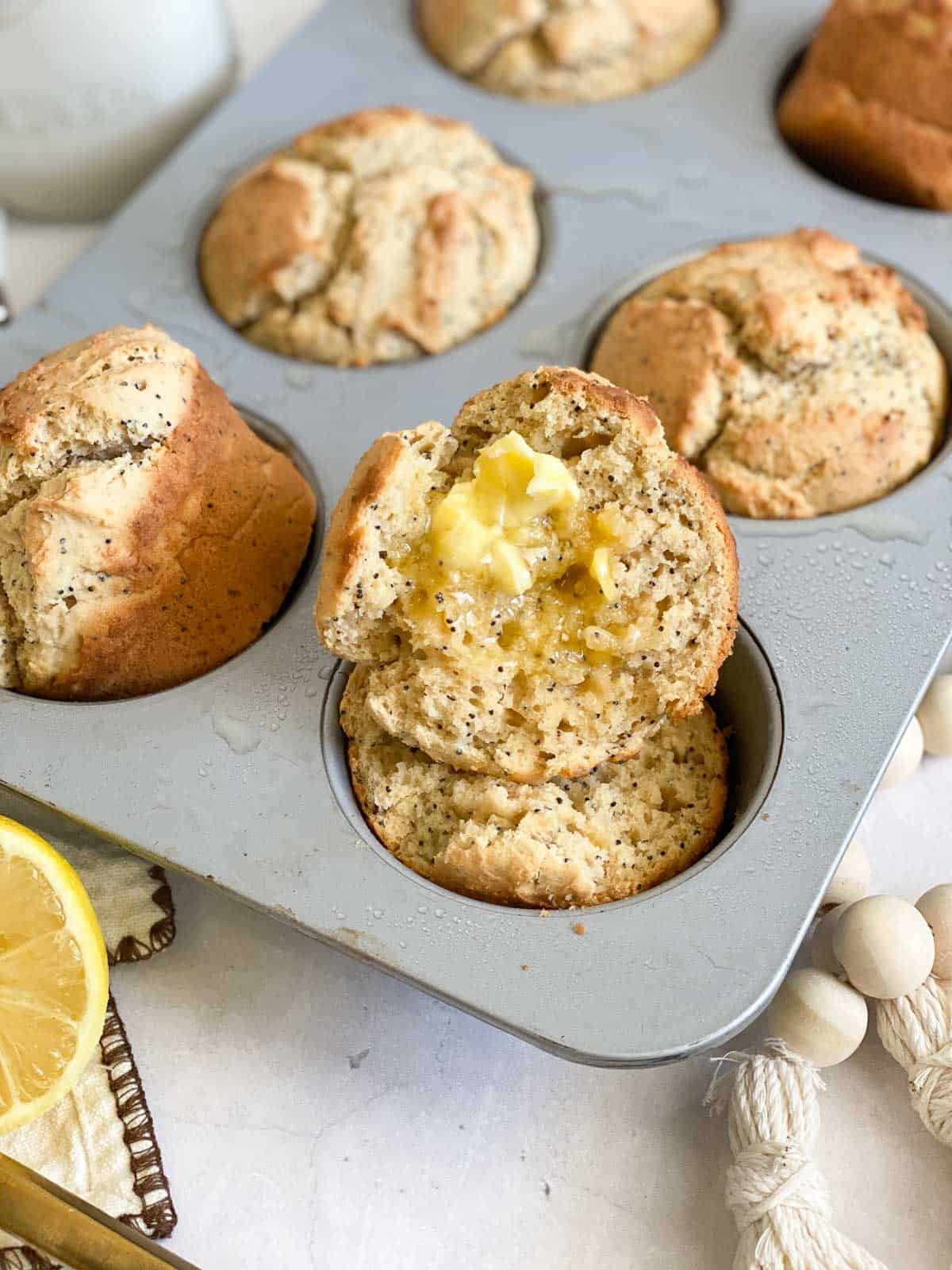 sourdough muffins with butter on one cut in half in muffin tin