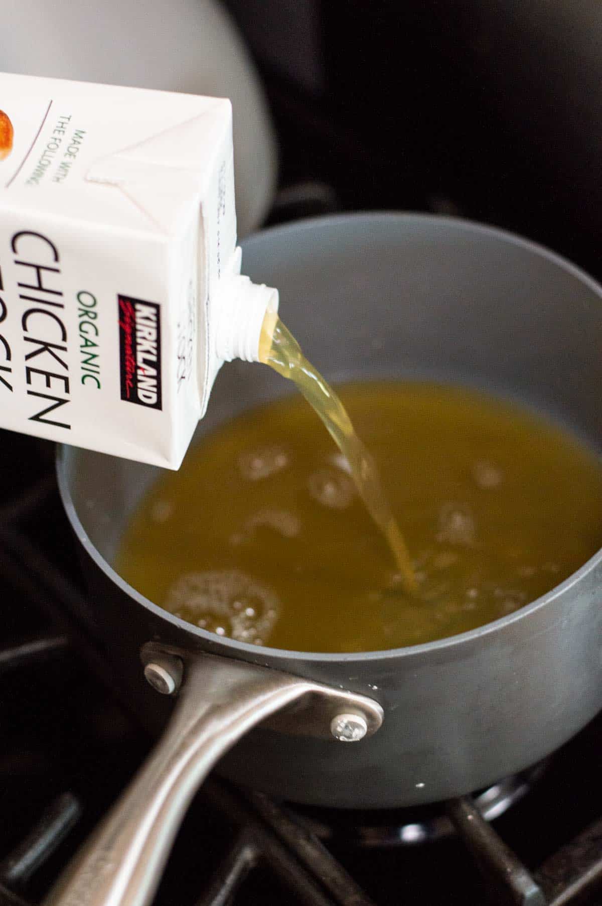 gluten free ramen with chicken stock being poured into pan on the stove