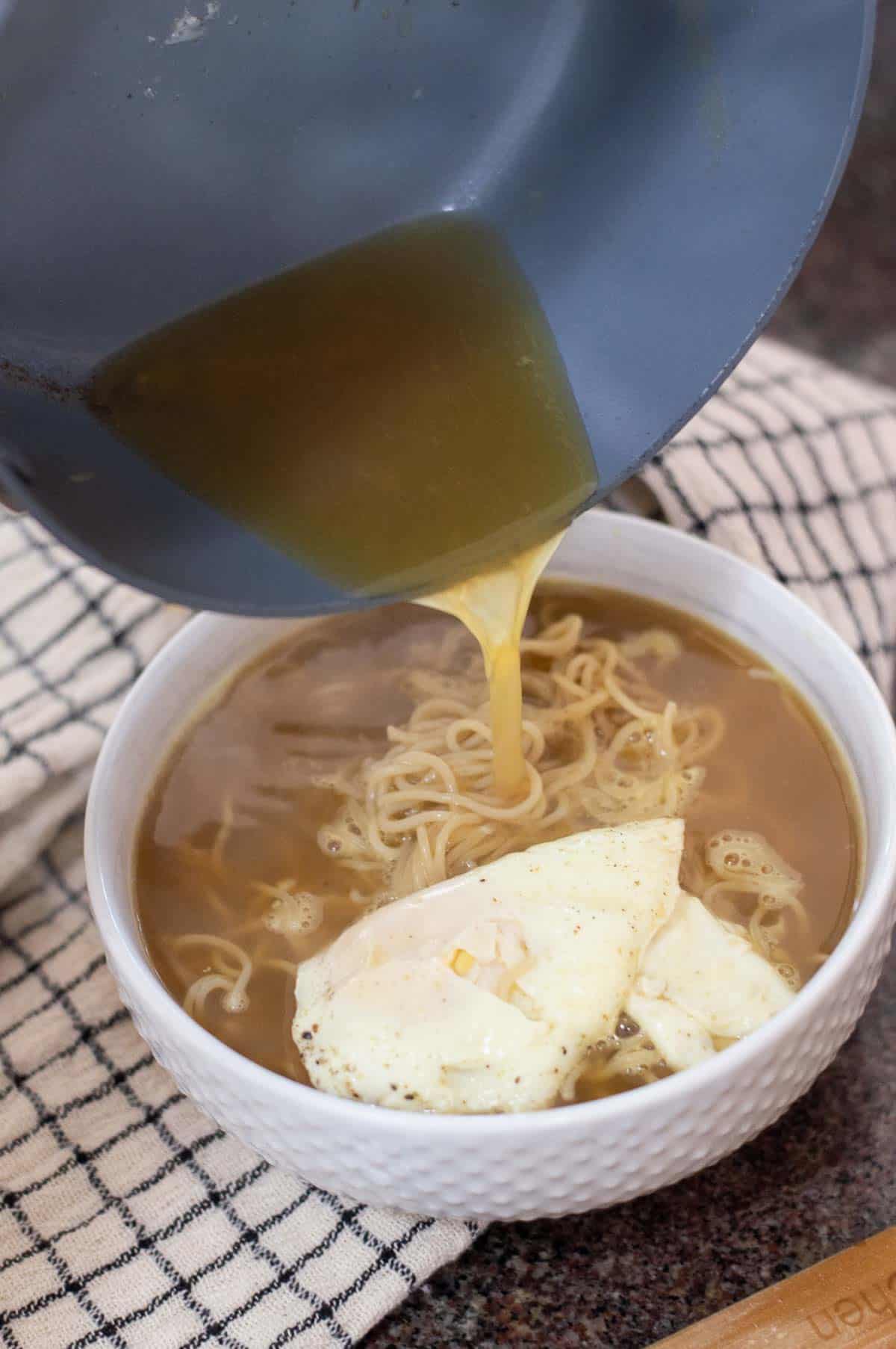 Gluten free ramen being poured into a bowl with an egg on top 