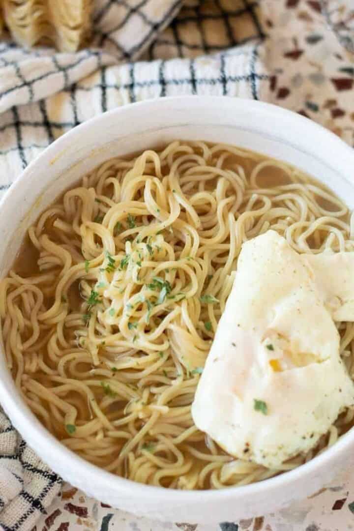 gluten free ramen in a white bowl with egg on top and seasoning
