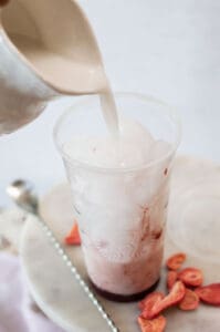 Starbucks Pink Drink Copycat in a plastic cup with coconut milk being poured in