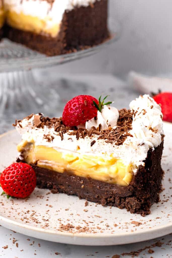 Slice of Gluten Free Banana Black Bottom Pie with a cookie crumb layer, banana pudding layer, and whipped cream layer sitting on a plate
