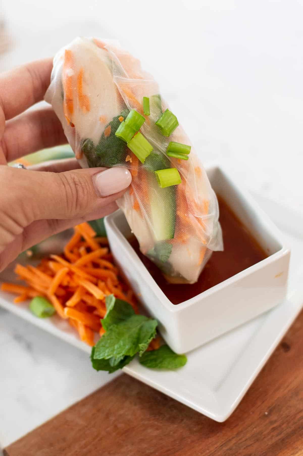 gluten free spring rolls being dipped in sauce