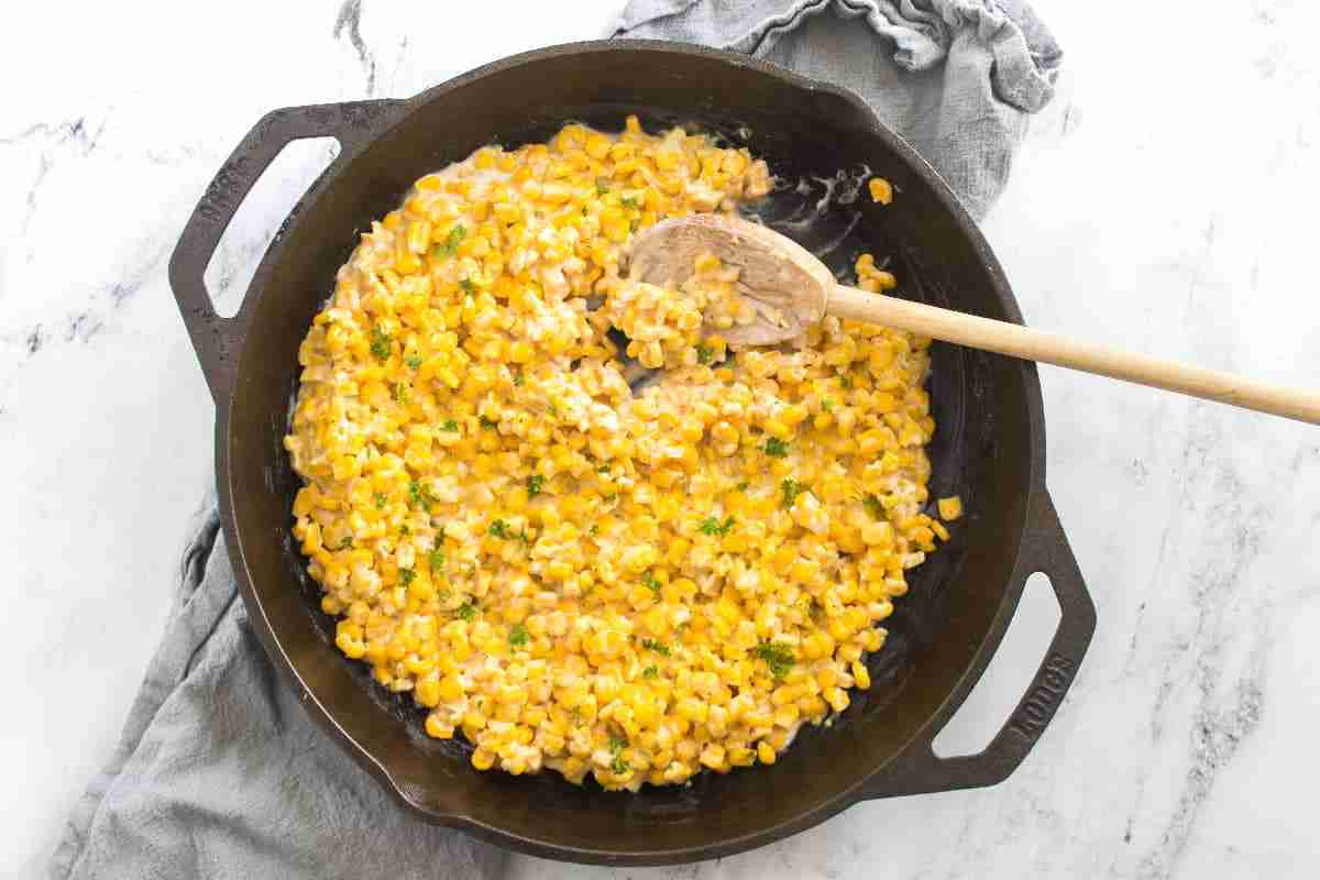 Honey butter skillet corn with a wooden spoon stirring the corn