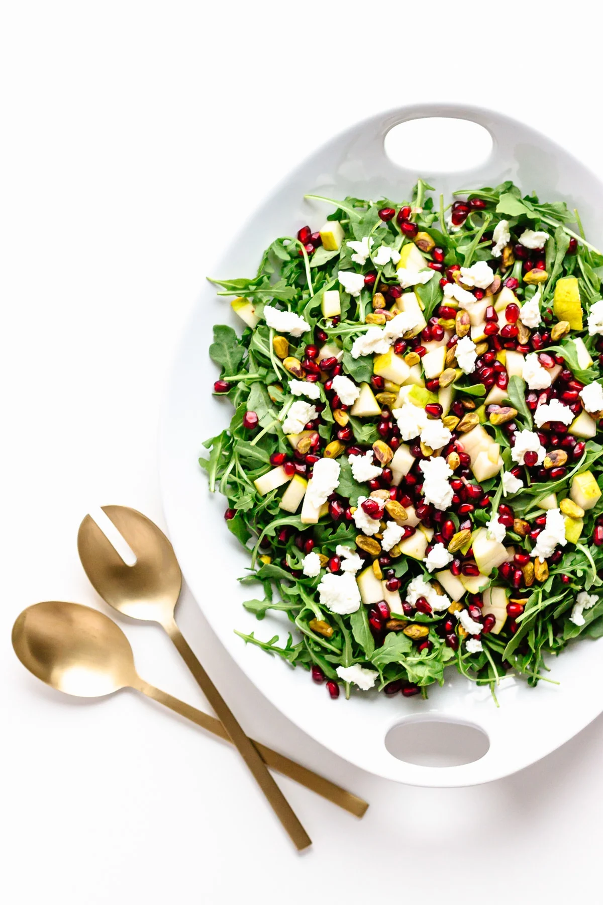 Winter holiday salad with pomegranate seeds, pears, goat cheese, and pistachios