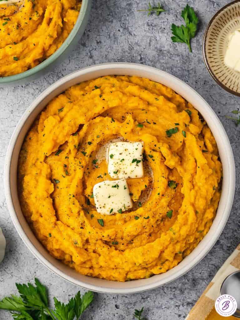 Mashed sweet potatoes topped with garnish and melted butter