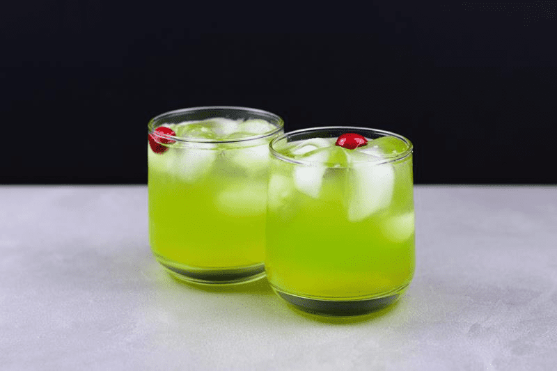 Grinch mocktail: bright green drink with ice cubes and cherry