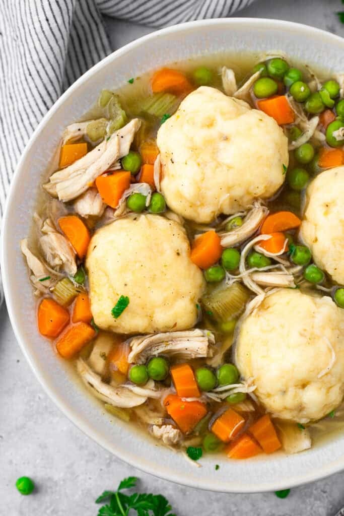 Top down image of gluten free chicken and dumplings in a white bowl with a spoon