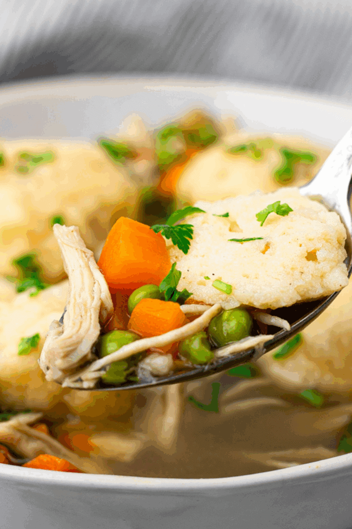 square image of spoon full or chicken and dumplings with bowl of gluten free chicken and dumplings in the back