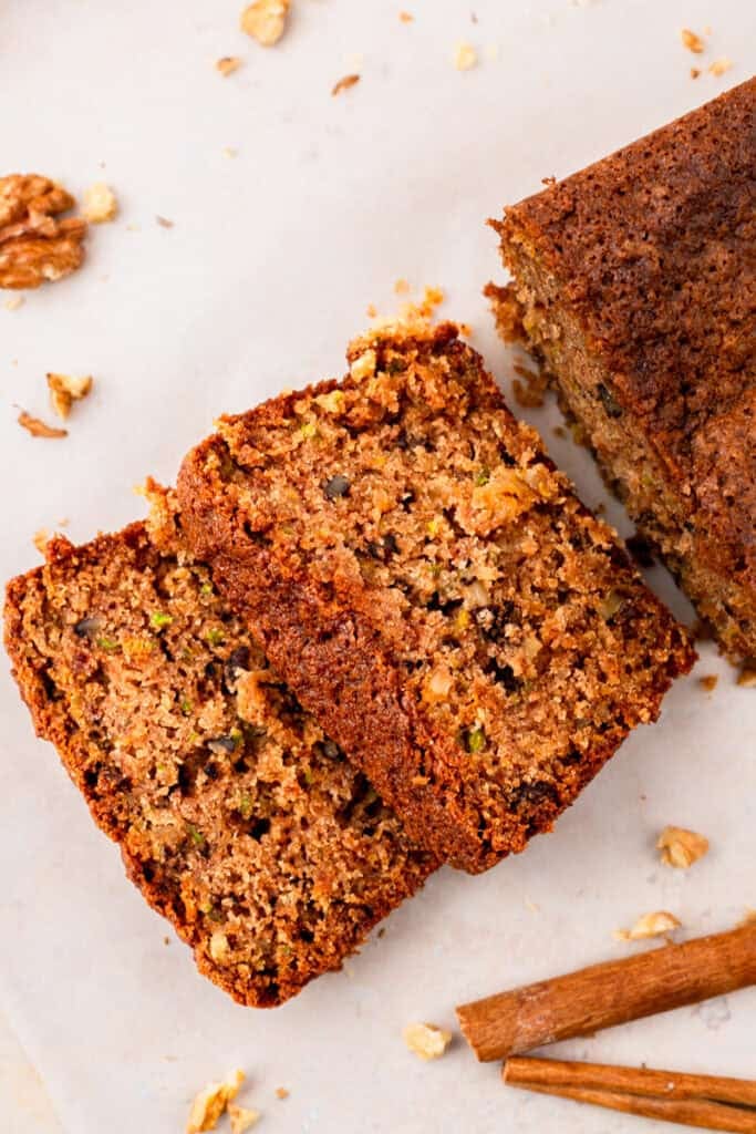 top down image of Extra Moist Gluten Free Zucchini Bread with slices of bread cut off of the loaf sitting on a counter with crumbs