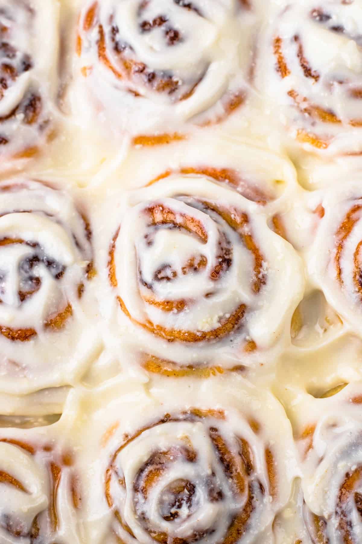 Close up of a top view of gluten-free cinnamon rolls slathered in frosting.
