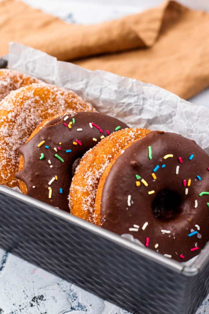Gluten Free Donuts (Fried, Bakery Style) in a tray with chocolate frosting and sugared outsides