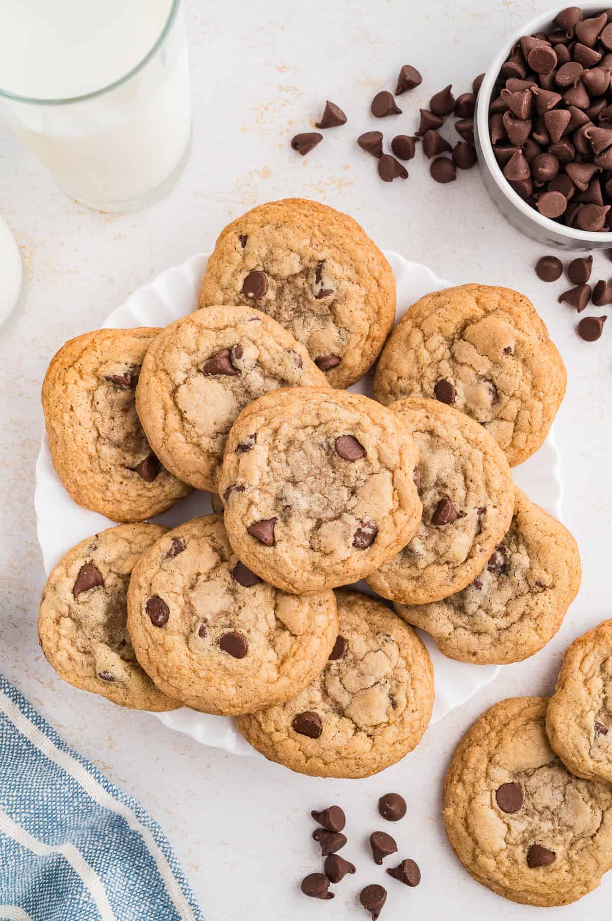 Gluten free chocolate chip cookies on a plate with chocolate chips off the plate by the side.