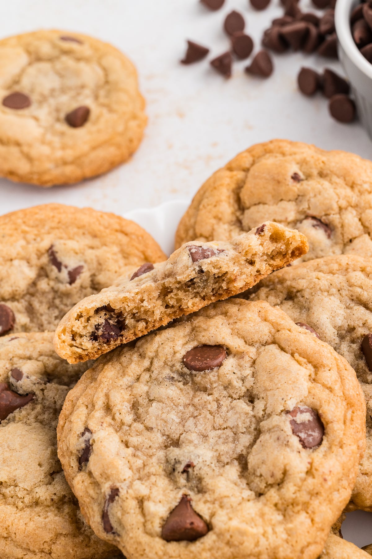 Gluten free chocolate chip cookies on a plate with one broken in half so you can see the inside.