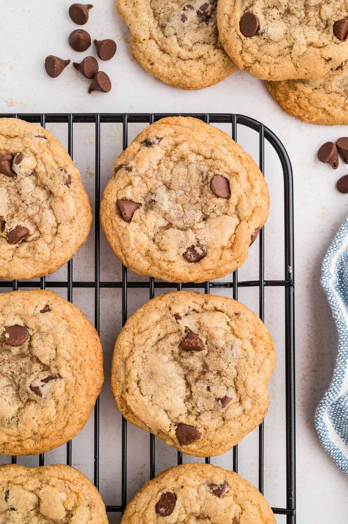 Gluten free chocolate chip cookies on a wire rack with chocolate chips off to the side.