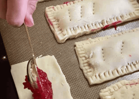 gluten free pop tarts being made with spoon of raspberry filling going into the pastry dough