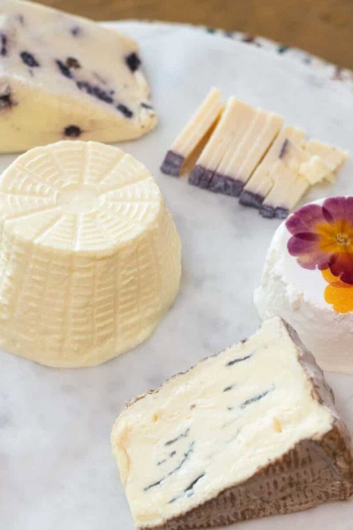 multiple cheeses on a marble charcuterie board