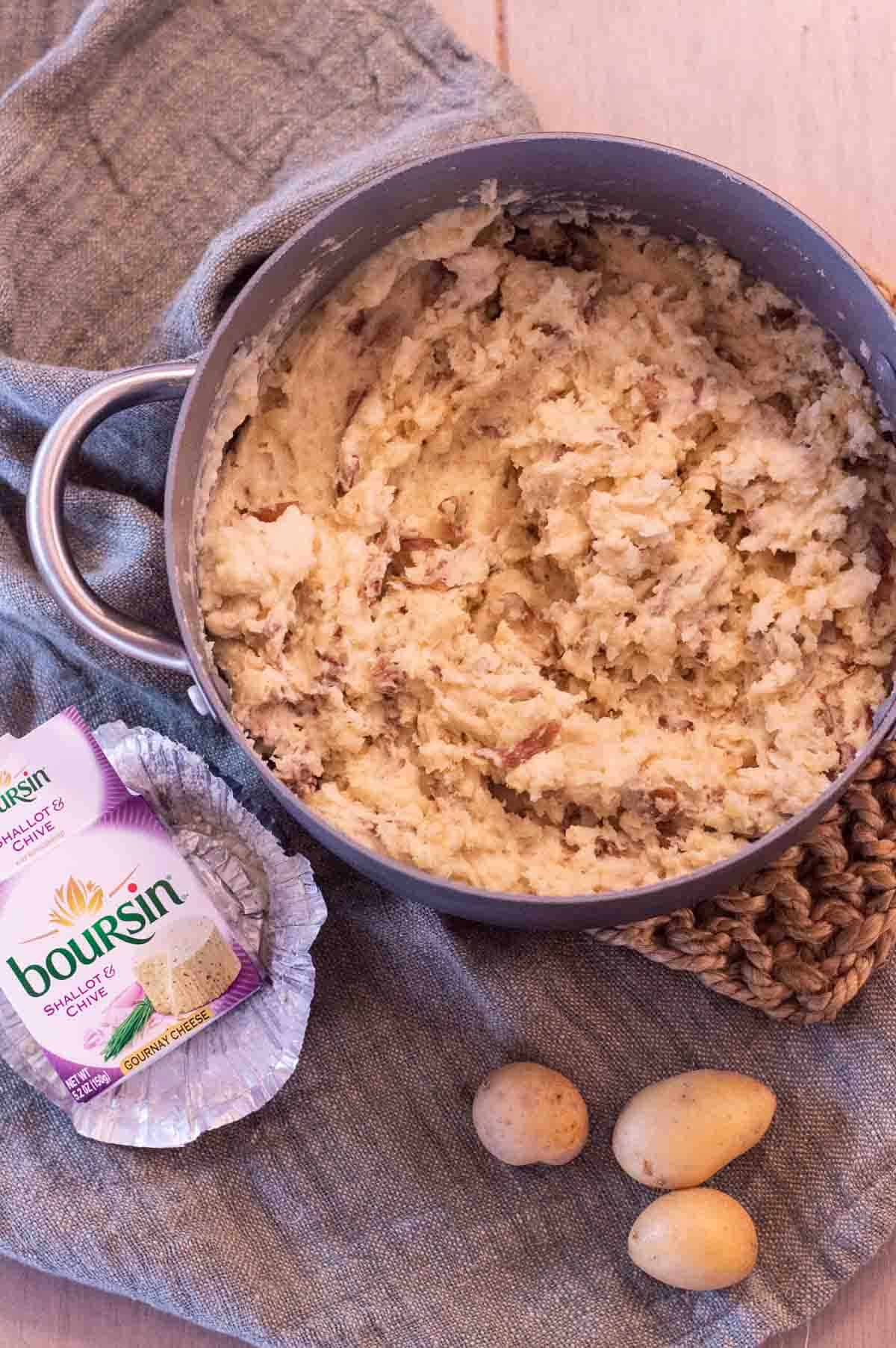 Boursin Mashed Potatoes in a pot with the Boursin cheese near it