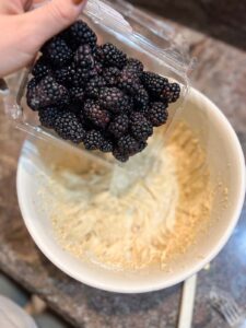 Gluten Free Blackberry Muffins step by step instructions blackberries being poured into batter