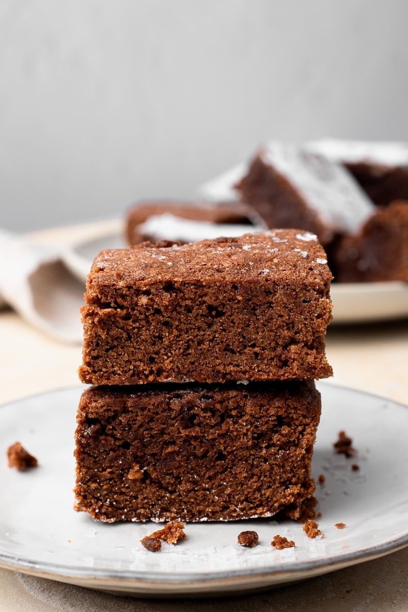 two gluten free brownies stacked on top of each other on a plate to show texture
