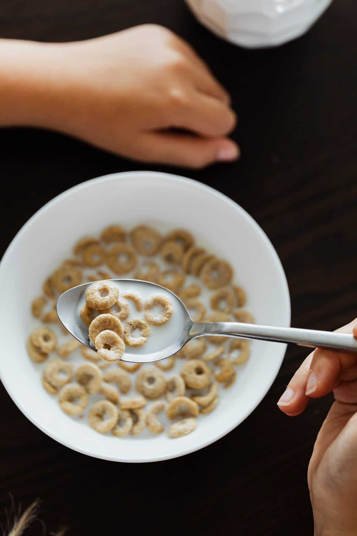 Gluten Free Cereal in a white bowl with a spoon in a hand